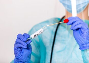 Lab technician holding swab collection kit,Coronavirus COVID-19 specimen collecting equipment,DNA nasal and oral swabbing for PCR polymerase chain reaction laboratory testing procedure and shipping